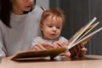 Bébé déchiffrant un livre et installé sur les genoux d'une femme adulte